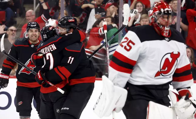 Carolina Hurricanes' Logan Stankoven, left hugs Logan Stankoven (22) following his goal with New Jersey Devils Jacob Markstrom (25) nearby during the second period of Game 1 of an NHL hockey Stanley Cup first-round playoff series in Raleigh, N.C., Sunday, April 20, 2025. (AP Photo/Karl DeBlaker)