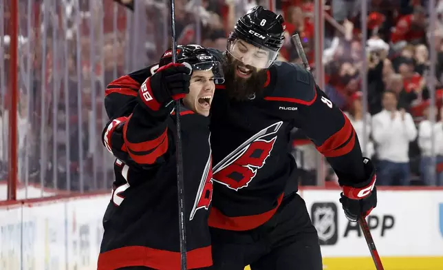 Carolina Hurricanes' Logan Stankoven (22) left, celebrates his goal with Brent Burns (8) during the second period of Game 1 of an NHL hockey Stanley Cup first-round playoff series against the New Jersey Devils in Raleigh, N.C., Sunday, April 20, 2025. (AP Photo/Karl DeBlaker)