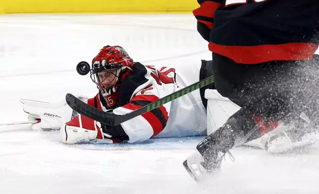 New Jersey Devils goaltender Jacob Markstrom (25) watches the shot of Carolina Hurricanes' William Carrier (28) bounce nearby during the second period of Game 1 of an NHL hockey Stanley Cup first-round playoff series in Raleigh, N.C., Sunday, April 20, 2025. (AP Photo/Karl DeBlaker)