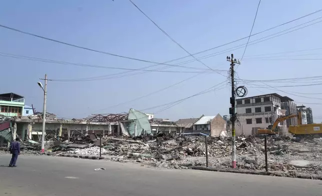 A volunteer drives a backhoe to clear debris of a building at a market, after one month of the strong earthquake in Naypyitaw, Myanmar, Monday, April 28, 2025. (AP Photo/Aung Shine Oo)