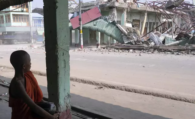 A Buddhist novice monk walks past damaged buildings at a market after one month of strong earthquake in Naypyitaw, Myanmar, Monday, April 28, 2025. (AP Photo/Aung Shine Oo)