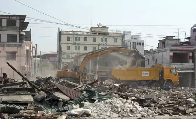 A volunteer drives a backhoe to clear debris of a building at a market, after one month of the strong earthquake in Naypyitaw, Myanmar, Monday, April 28, 2025. (AP Photo/Aung Shine Oo)