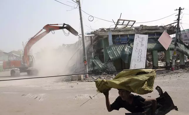 A women walks past damaged buildings at a market, after one month of the strong earthquake in Naypyitaw, Myanmar, Monday, April 28, 2025. (AP Photo/Aung Shine Oo)