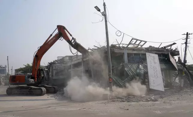 A volunteer drives a backhoe to clear debris of a building at a market, after one month of the strong earthquake in Naypyitaw, Myanmar, Monday, April 28, 2025. (AP Photo/Aung Shine Oo)