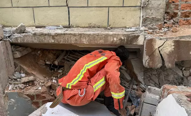A firefighter recovers the belongings of victims from damaged buildings that house Governments' servants in Naypyitaw, Myanmar, Monday, April 28, 2025, one month after the earthquake. (AP Photo/Aung Shine Oo)
