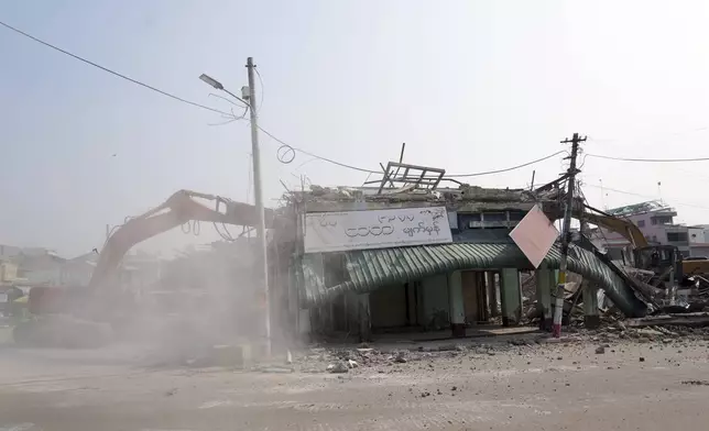 A volunteer drives a backhoe to clear debris of a building at a market, after one month of the strong earthquake in Naypyitaw, Myanmar, Monday, April 28, 2025. (AP Photo/Aung Shine Oo)