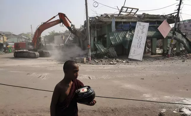 A Buddhist novice monk walks past damaged buildings at a market, after one month of the strong earthquake in Naypyitaw, Myanmar, Monday, April 28, 2025. (AP Photo/Aung Shine Oo)