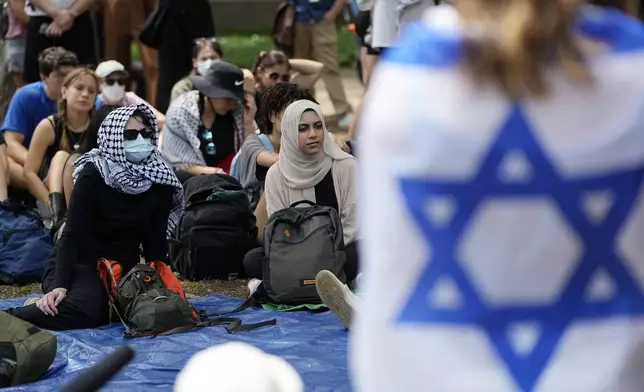 FILE - A student wrapped in an Israeli flag listens to Pro-Palestinian protesters gathered on campus at the University of Texas at Austin, on April 30, 2024, in Austin, Texas. (AP Photo/Eric Gay, File)