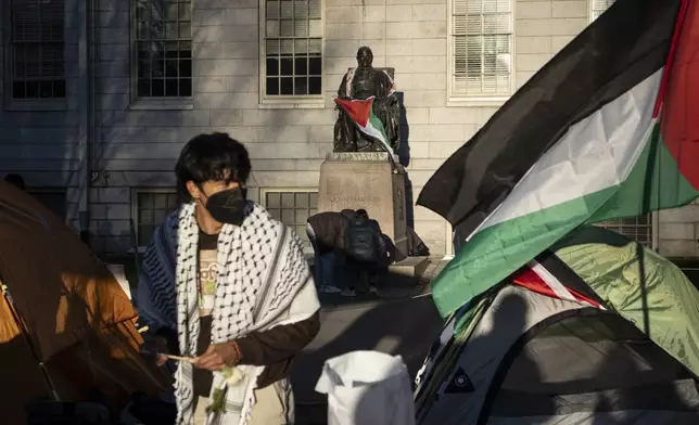 FILE - A student protester stands in front of the statue of John Harvard, the first major benefactor of Harvard College, draped in the Palestinian flag, at an encampment of students protesting against the war in Gaza, at Harvard University in Cambridge, Mass., on April 25, 2024. (AP Photo/Ben Curtis)