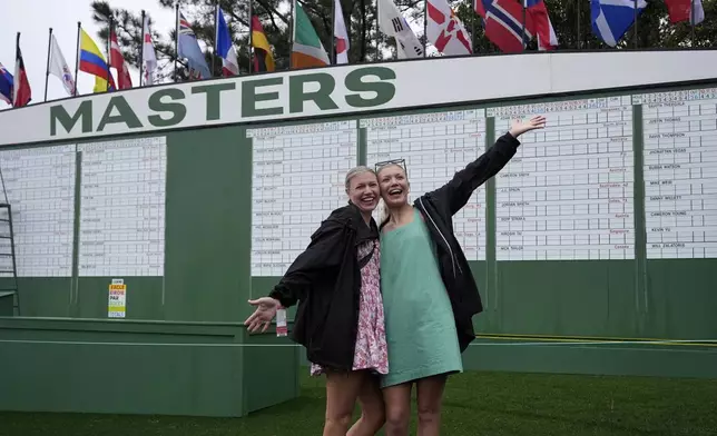 Karlee Lambert, left, and Kaylee Aiken have their picture taken in front of the scoreboard during a practice around at the Masters golf tournament, Monday, April 7, 2025, in Augusta, Ga. (AP Photo/George Walker IV)