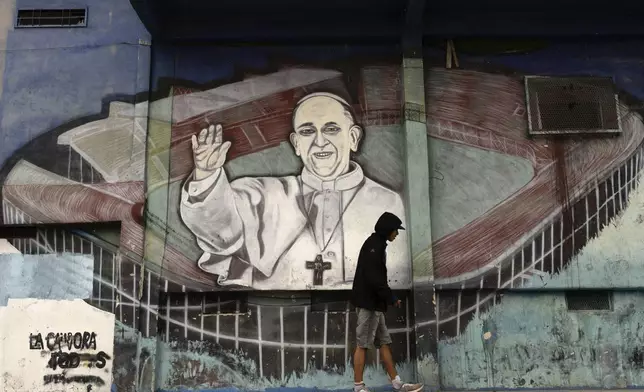 FILE - A man walks past a mural of Pope Francis at the stadium of San Lorenzo, his soccer team, in the Padre Ricciardelli neighborhood of Buenos Aires, Argentina, Feb. 25, 2025. (AP Photo/Rodrigo Abd, File)