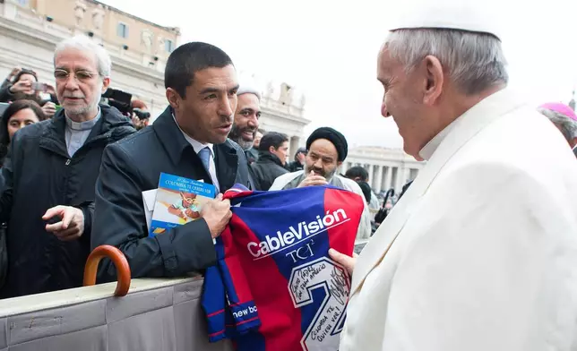 FILE - Pope Francis is presented with a San Lorenzo soccer team jersey by Colombian former player Ivan Ramiro Cordoba during the pontiff's weekly general audience in St. Peter's square at the Vatican, March 25, 2015. (AP Photo/L'Osservatore Romano, File)
