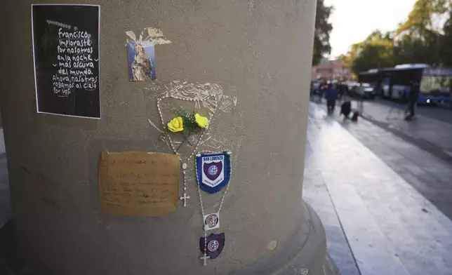 A rosary, messages, and emblems of the San Lorenzo soccer club, of which the late Pope Francis was a fan, are attached to a column of the Cathedral in Buenos Aires, Argentina, following his passing on Monday, April 21, 2025. (AP Photo/Natacha Pisarenko)