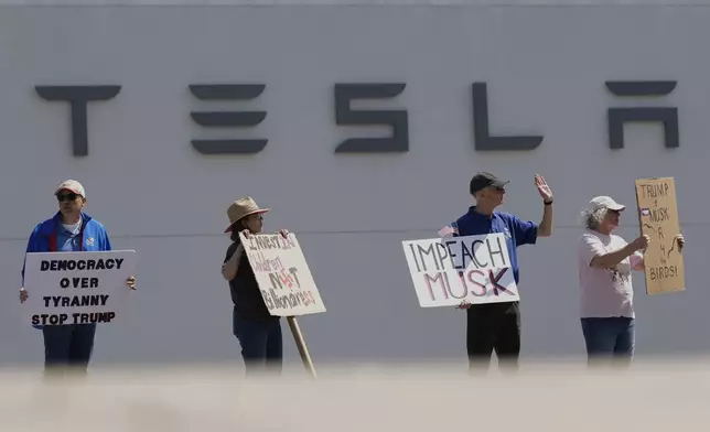 Demonstrators protest against Elon Musk and Department of Government Efficiency cuts outside a Tesla dealership, Saturday, April 12, 2025, in Kansas City, Mo. (AP Photo/Charlie Riedel)