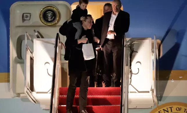 Elon Musk, left, carries his son, X Æ A-Xii, down the stairs of Air Force One upon President Donald Trump's arrival at Joint Base Andrews, Md., Sunday, April 13, 2025. (AP Photo/Luis M. Alvarez)