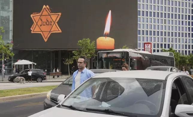 People stand next to their cars during a two-minute siren marking the annual Israeli Holocaust Remembrance Day in Tel Aviv, Israel, Thursday, April 24, 2025. (AP Photo/Ohad Zwigenberg)