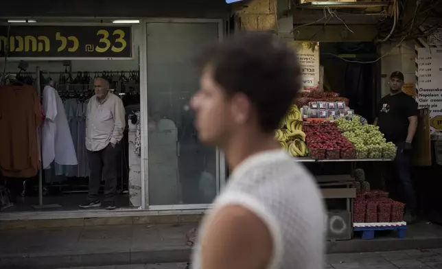 People stand still during a two-minute siren marking the annual Israeli Holocaust Remembrance Day at the Mahane Yehuda market, in Jerusalem, Thursday, April 24, 2025. (AP Photo/Leo Correa)