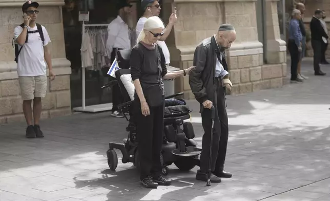 People stand still during a two-minute siren marking the annual Israeli Holocaust Remembrance Day, in Jerusalem on Thursday, April 24, 2025. (AP Photo/Mahmoud Illean)