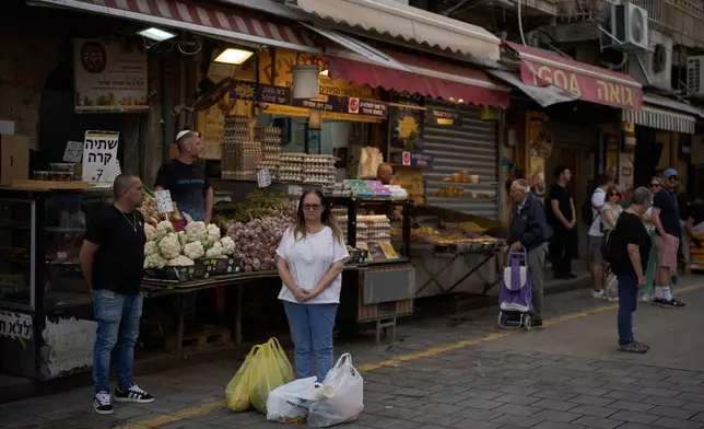 People stand still during a two-minute siren marking the annual Israeli Holocaust Remembrance Day at the Mahane Yehuda market, in Jerusalem, Thursday, April 24, 2025. (AP Photo/Leo Correa)