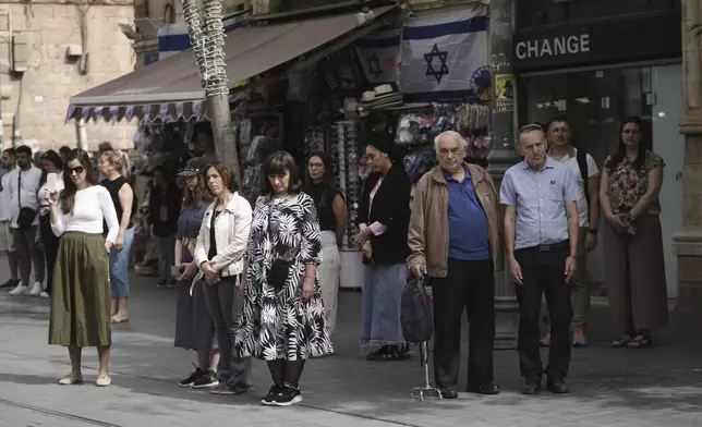 People stand still during a two-minute siren marking the annual Israeli Holocaust Remembrance Day, in Jerusalem on Thursday, April 24, 2025. (AP Photo/Mahmoud Illean)