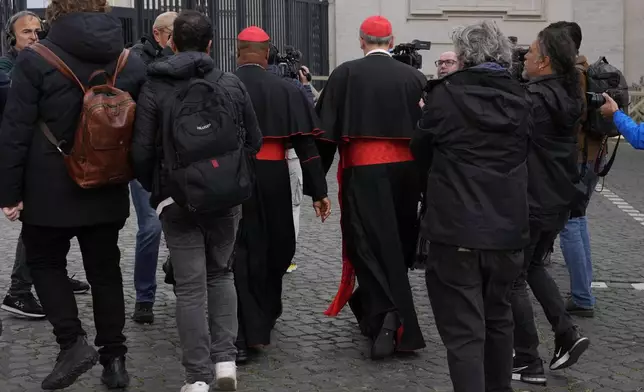 Cardinal Pierbattista Pizzaballa, center right, and Cardinal Fridolin Ambongo Besungu are surrounded by reporters as they arrive for a college of cardinals' meeting, at the Vatican, Monday, April 28, 2025. (AP Photo/Gregorio Borgia)