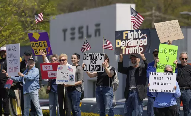 Demonstrators protest against Elon Musk and Department of Government Efficiency cuts outside a Tesla dealership, Saturday, April 12, 2025, in Kansas City, Mo. (AP Photo/Charlie Riedel)
