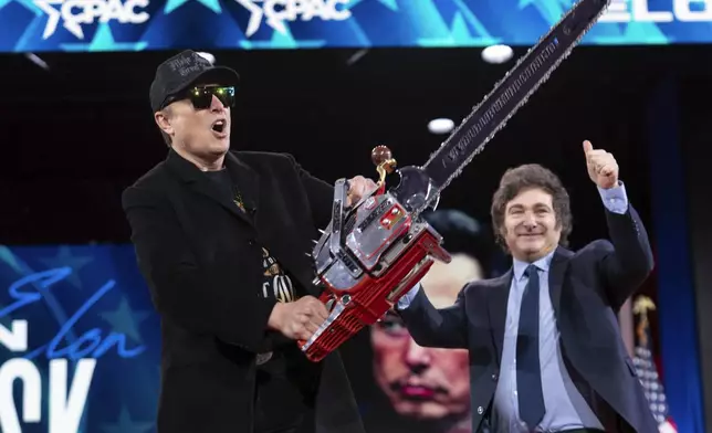 Elon Musk holds up a chainsaw he received from Argentina's President Javier Milei, right, as they arrive to speak at the Conservative Political Action Conference, CPAC, at the Gaylord National Resort &amp; Convention Center, Thursday, Feb. 20, 2025, in Oxon Hill, Md. (AP Photo/Jose Luis Magana)