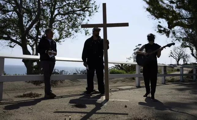 Carli Wright, right, plays a song during a Cross Walk event by the Community United Methodist Church of the Pacific Palisades, Friday, April 18, 2025, in the Pacific Palisades area of Los Angeles. (AP Photo/William Liang)