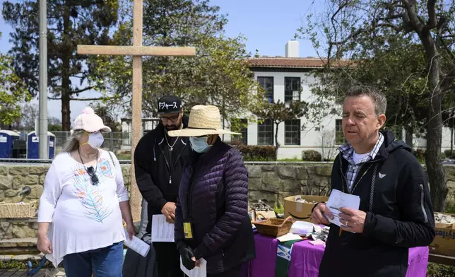 Members of a church listen to a prayer by Pastor John Shaver, right, during a Cross Walk event by the Community United Methodist Church of the Pacific Palisades, Friday, April 18, 2025, in the Pacific Palisades area of Los Angeles. (AP Photo/William Liang)