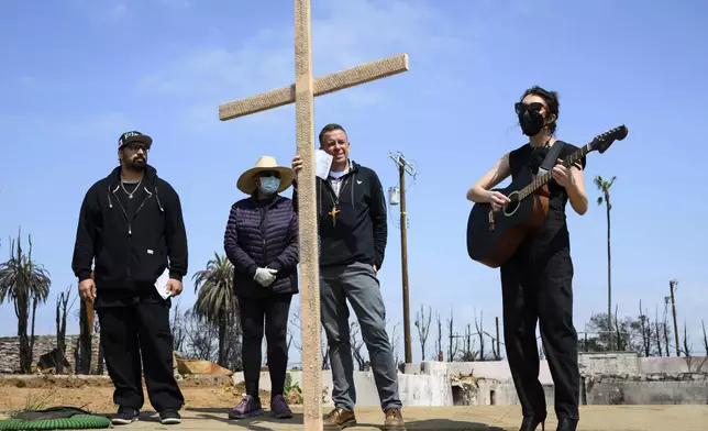 Carli Wright, right, plays music for a church prayer during a Cross Walk event by the Community United Methodist Church of the Pacific Palisades, Friday, April 18, 2025, in the Pacific Palisades area of Los Angeles. (AP Photo/William Liang)