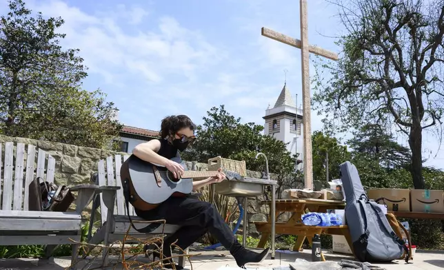 Carli Wright plays music during a Cross Walk event by the Community United Methodist Church of the Pacific Palisades, Friday, April 18, 2025, in the Pacific Palisades area of Los Angeles. (AP Photo/William Liang)