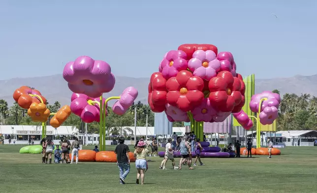 Festivalgoers are seen around the art installation Uchronia / Le Grand Bouquet during the first weekend of the Coachella Valley Music and Arts Festival at the Empire Polo Club on Friday, April 11, 2025, in Indio, Calif. (Photo by Amy Harris/Invision/AP)