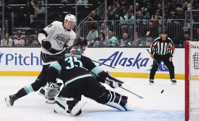 Los Angeles Kings center Samuel Helenius scores against Seattle Kraken goaltender Joey Daccord (35) and defenseman Ryker Evans, center, during the third period of an NHL hockey game Tuesday, April 15, 2025, in Seattle. (AP Photo/Lindsey Wasson)