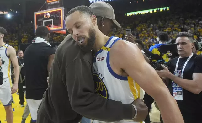 Golden State Warriors guard Stephen Curry, foreground, celebrates with injured forward Jimmy Butler III after Game 3 of an NBA basketball first-round playoff series against the Houston Rockets in San Francisco, Saturday, April 26, 2025. (AP Photo/Jeff Chiu)