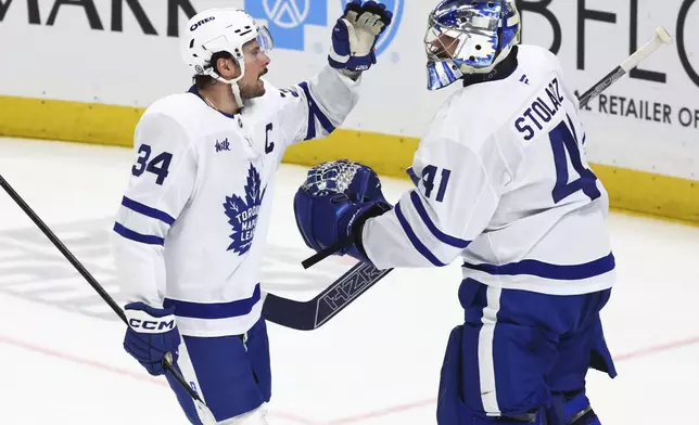 Toronto Maple Leafs center Auston Matthews (34) celebrates his goal with goaltender Anthony Stolarz (41) during the third period of an NHL hockey game against the Buffalo Sabres, Tuesday, April 15, 2025, in Buffalo, N.Y. (AP Photo/Jeffrey T. Barnes)