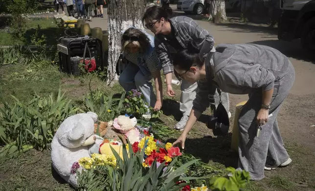 People lay flowers and toys on the site of Russia's deadly missile attack that hit residential houses Thursday killing 12 civilians and injuring 87 in Kyiv, Ukraine, Friday, April 25, 2025. (AP Photo/Efrem Lukatsky)