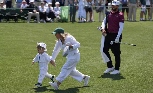 Matthieu Pavon, of France, walks to the green on the first hole as his wife, Melissa Tarris runs with their son Aaron, 2, during the par-3 contest at the Masters golf tournament, Wednesday, April 9, 2025, in Augusta, Ga. (AP Photo/Ashley Landis)
