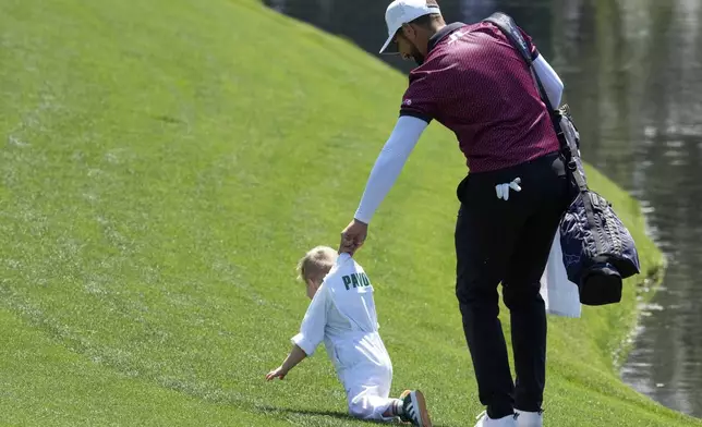 Matthieu Pavon, of France, lifts his son, Aaron, 2, on fifth hole during the par-3 contest at the Masters golf tournament, Wednesday, April 9, 2025, in Augusta, Ga. (AP Photo/George Walker IV)