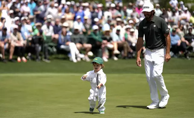 Max Homa and his son, Cam Homa, walks on green on the seventh hole during par-3 contest at the Masters golf tournament, Wednesday, April 9, 2025, in Augusta, Ga. (AP Photo/Julia Demaree Nikhinson)