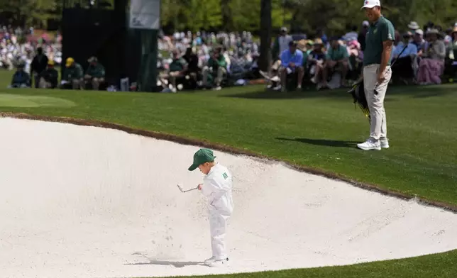 Byeong Hun An, of South Korea, watches his son, Sun-woo, 5, hit out of the bunker on the first hole during the par-3 contest at the Masters golf tournament, Wednesday, April 9, 2025, in Augusta, Ga. (AP Photo/Ashley Landis)