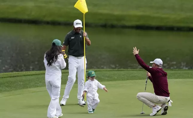 Max Homa, center, with son Cam Homa, laugh with Justin Thomas on the first hole during par-3 contest at the Masters golf tournament, Wednesday, April 9, 2025, in Augusta, Ga. (AP Photo/George Walker IV)