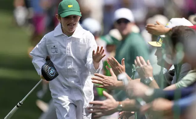 Lucas Glover's son, Lucas Jr., high fives patrons on the first hole during the par-3 contest at the Masters golf tournament, Wednesday, April 9, 2025, in Augusta, Ga. (AP Photo/Julia Demaree Nikhinson)