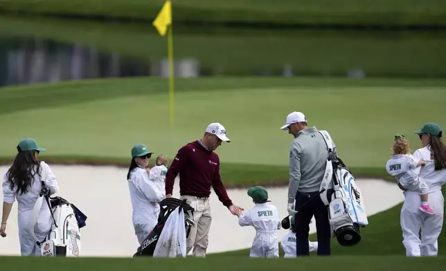 Jordan Spieth, right, holds his son Sammy's hand as he gives five to Justin Thomas, left, during the par-3 contest at the Masters golf tournament, Wednesday, April 9, 2025, in Augusta, Ga. (AP Photo/George Walker IV)