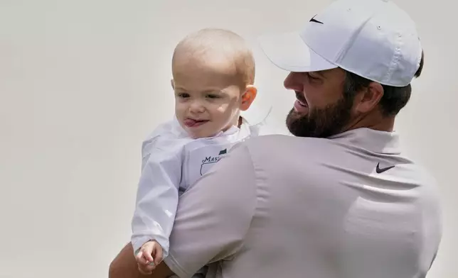 Scottie Scheffler holds his child Bennett on the first hole during the par-3 contest at the Masters golf tournament, Wednesday, April 9, 2025, in Augusta, Ga. (AP Photo/Ashley Landis)