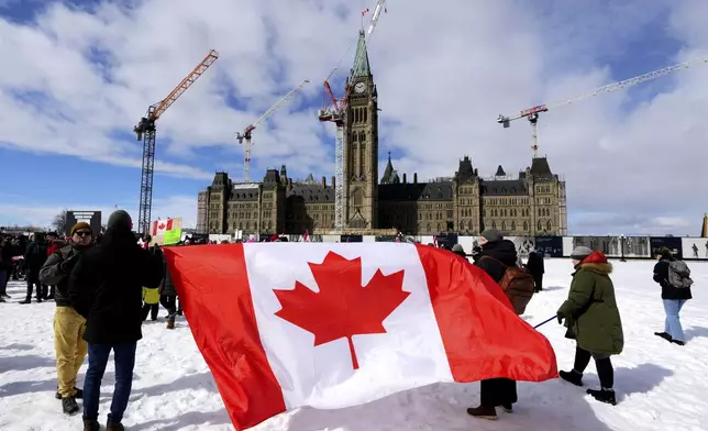 FILE - People hold a large Canadian flag during a rally in response to U.S. President Donald Trump's threats to Canadian sovereignty, on Parliament Hill in Ottawa, March 9, 2025. (Justin Tang/The Canadian Press via AP File)