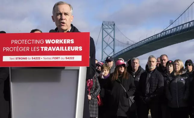FILE - Unifor auto workers stand behind Prime Minister Mark Carney as he speaks during a campaign stop in Windsor, Ont., March 26, 2025, near the Ambassador Bridge that connects Canada with the United States. (Frank Gunn /The Canadian Press via AP File)