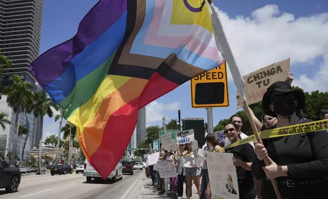 A person waves a rainbow flag during a protest against the Trump administration, Saturday, April 19, 2025, in Miami. (AP Photo/Lynne Sladky)