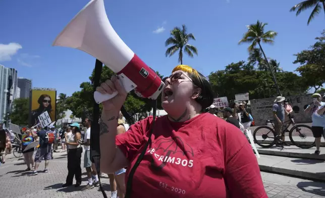 A person who gave their name as "Mistress Mei" chants slogans during a protest against the Trump administration, Saturday, April 19, 2025, in Miami. (AP Photo/Lynne Sladky)