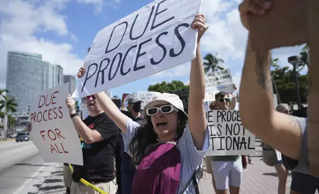 People hold signs and chant slogans during a protest against the Trump administration, Saturday, April 19, 2025, in Miami. (AP Photo/Lynne Sladky)