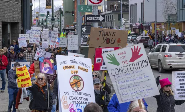 People walk through downtown Anchorage, Alaska, to protest against President Trump and his policies on Saturday, April 19, 2025. (Loren Holmes/Anchorage Daily News via AP)